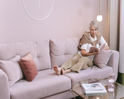 Senior person relaxing on sofa reading book